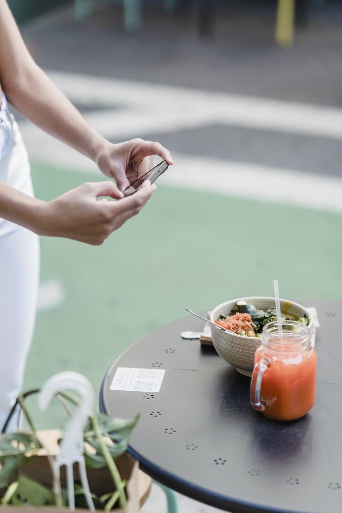 Faceless blogger taking photo of vegetarian food on smartphone
