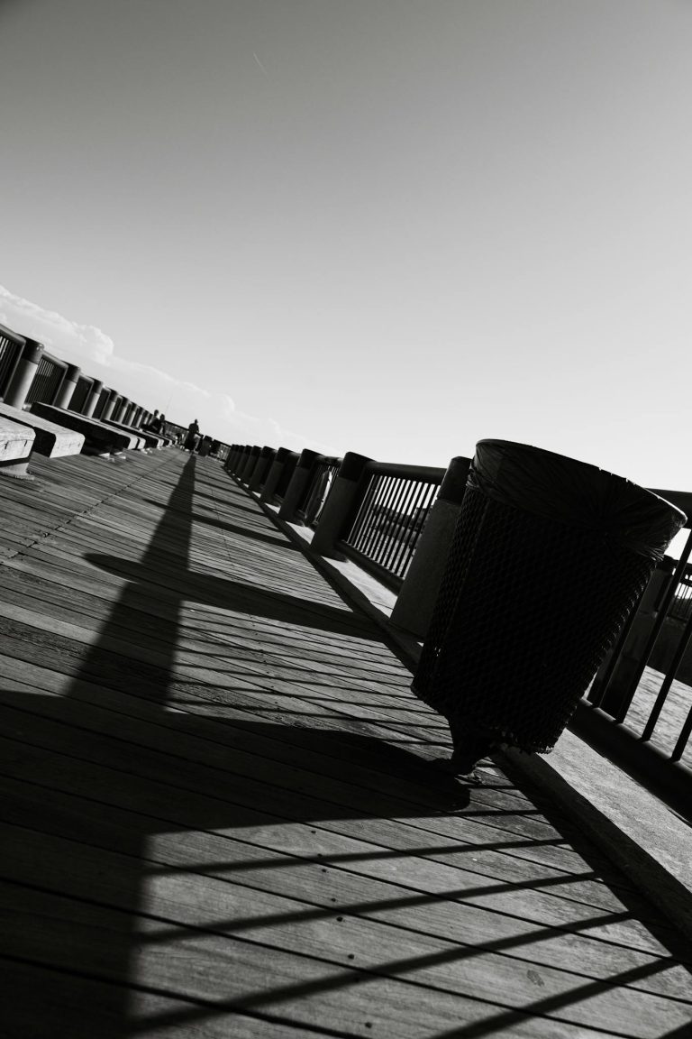 Moody black and white photo capturing shadows and lines on a wooden pier.