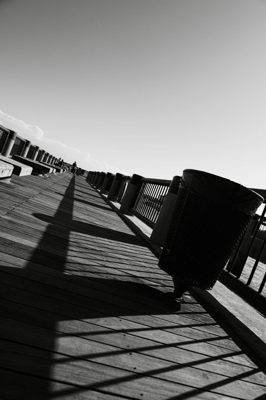 Moody black and white photo capturing shadows and lines on a wooden pier.